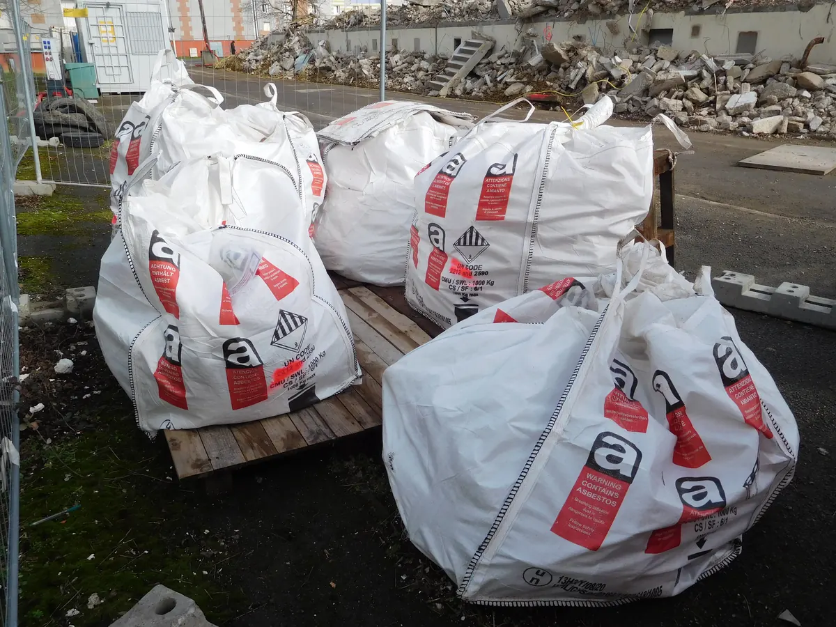 Grands sacs de déchets amiantés fermés et étiquetés sur un chantier