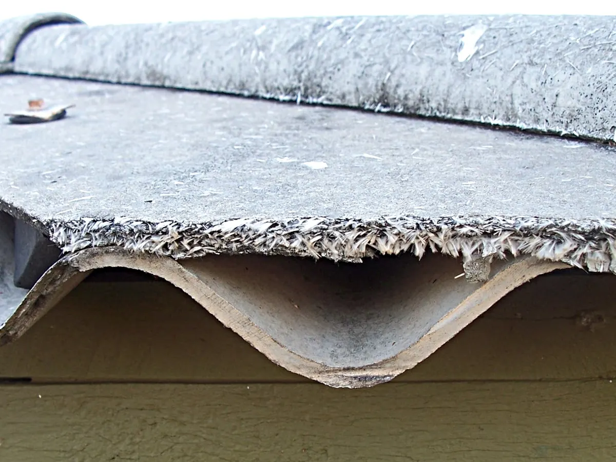Bord d'une plaque ondulée de fibrociment érodée, fibres apparentes